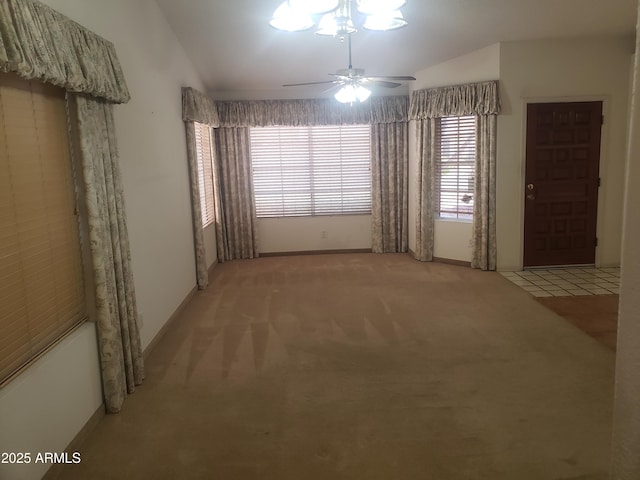 empty room featuring ceiling fan, lofted ceiling, and light carpet