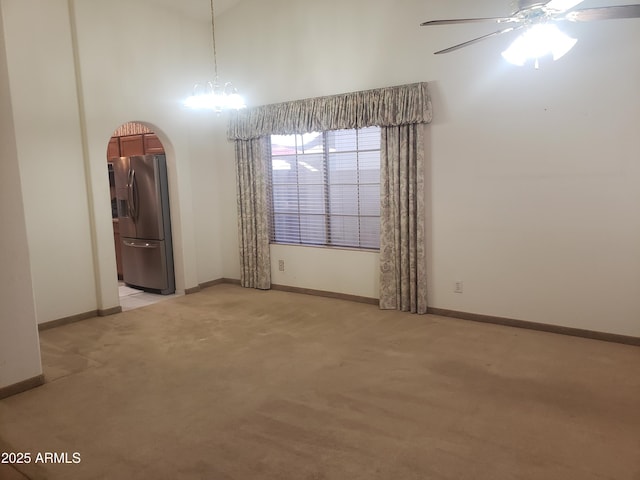 carpeted spare room with ceiling fan with notable chandelier