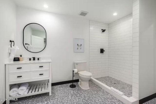 bathroom featuring vanity, toilet, tile patterned floors, and tiled shower