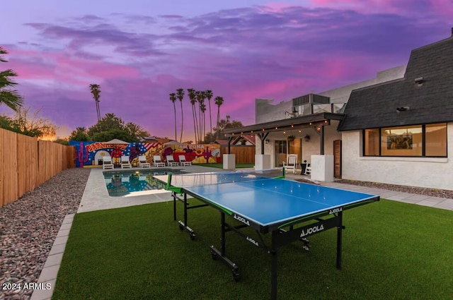 pool at dusk featuring a yard and a patio