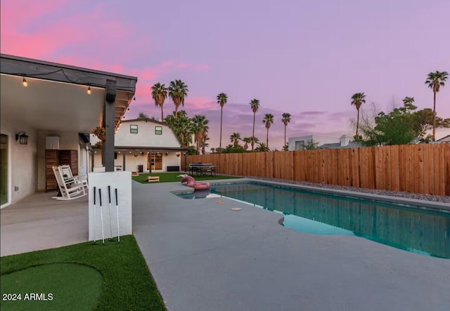 pool at dusk featuring a patio