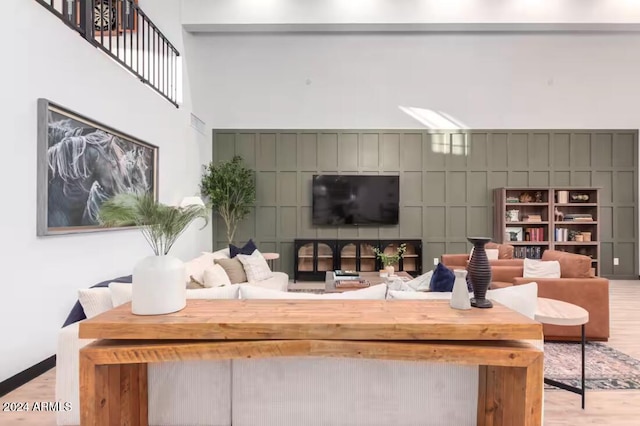 living room featuring a towering ceiling and light hardwood / wood-style flooring