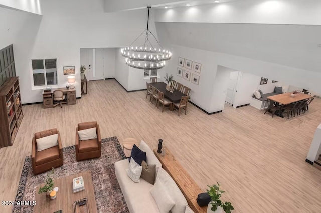 living room with hardwood / wood-style flooring, a towering ceiling, and a chandelier