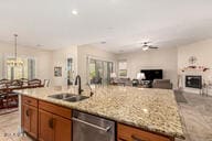 kitchen featuring dishwasher, light stone counters, sink, and a chandelier