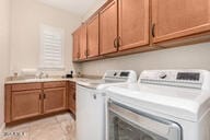 washroom featuring washer and clothes dryer, light tile patterned floors, cabinets, and sink