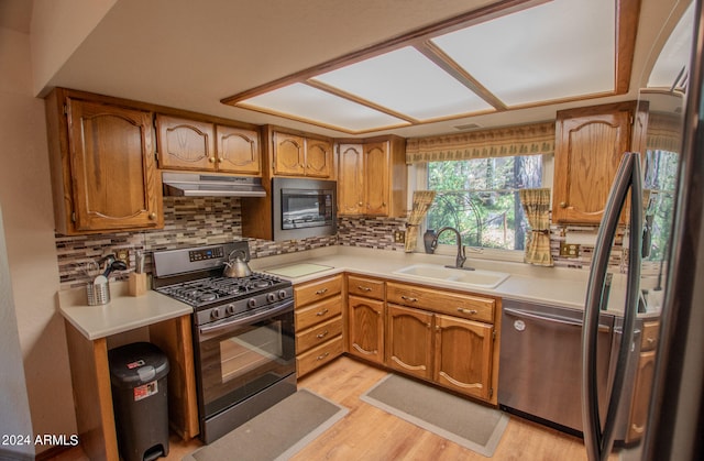 kitchen featuring sink, stainless steel appliances, light wood-type flooring, and tasteful backsplash