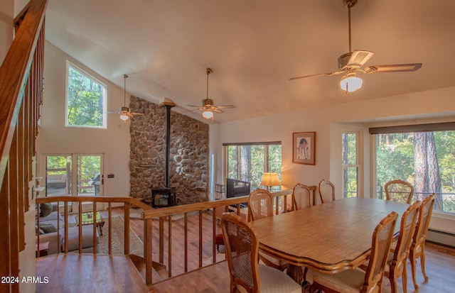 dining room with light hardwood / wood-style floors, a wood stove, and a wealth of natural light