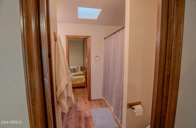 bathroom featuring hardwood / wood-style floors, a shower with curtain, and a skylight