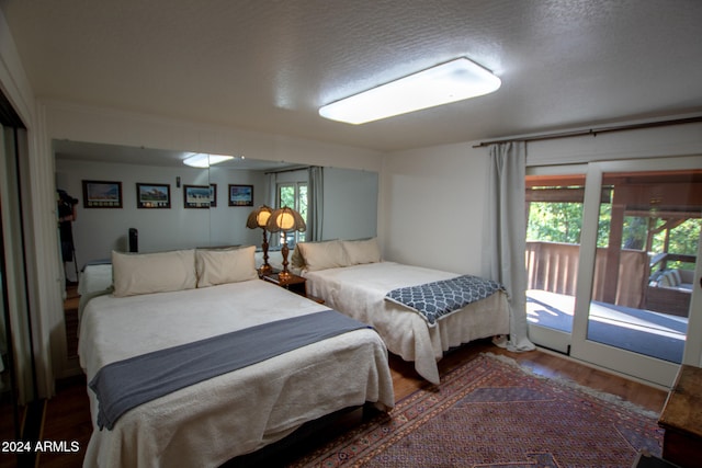 bedroom with access to outside, a textured ceiling, and hardwood / wood-style flooring