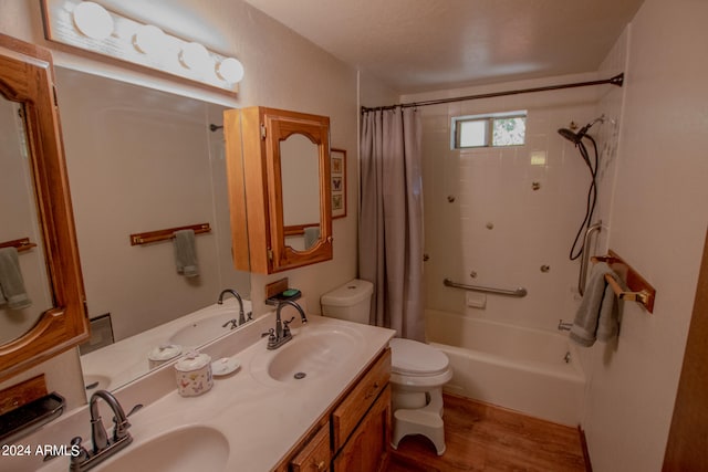 full bathroom featuring toilet, shower / tub combo, wood-type flooring, vanity, and a textured ceiling