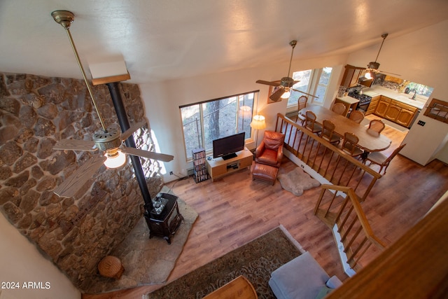 living room with a healthy amount of sunlight, lofted ceiling, wood-type flooring, and a wood stove