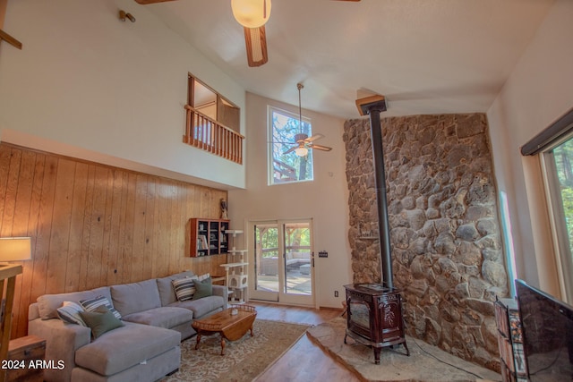 living room with a wealth of natural light, a high ceiling, light wood-type flooring, and a wood stove