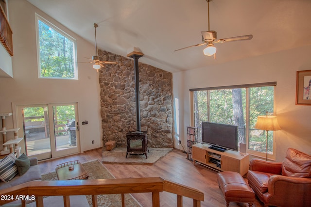 living room with light hardwood / wood-style flooring, a wood stove, plenty of natural light, and ceiling fan