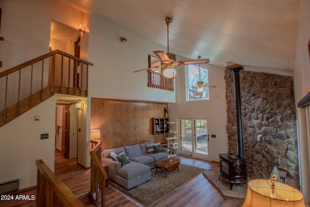 living room with high vaulted ceiling, wood walls, a baseboard heating unit, a wood stove, and hardwood / wood-style flooring