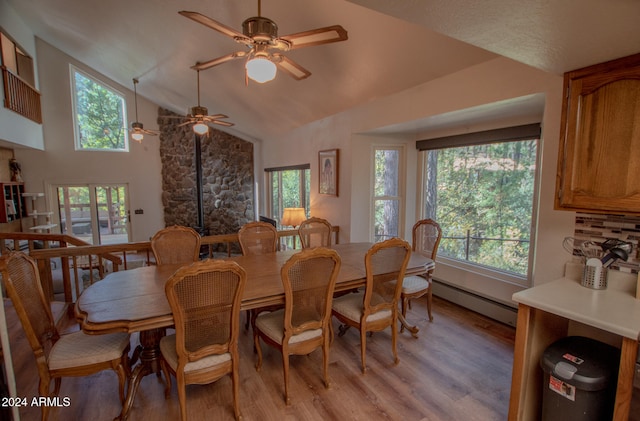 dining space with baseboard heating, vaulted ceiling, a healthy amount of sunlight, and ceiling fan