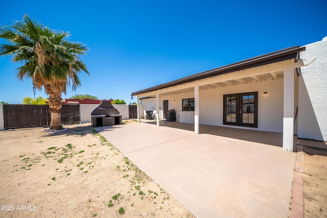back of house with a patio, a fireplace, stucco siding, french doors, and fence