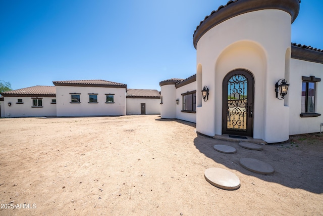 back of property featuring a tile roof and stucco siding