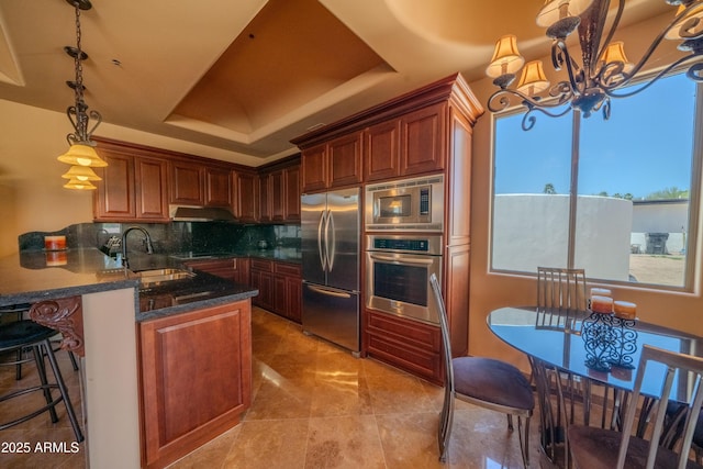 kitchen featuring tasteful backsplash, a chandelier, stainless steel appliances, a sink, and a peninsula