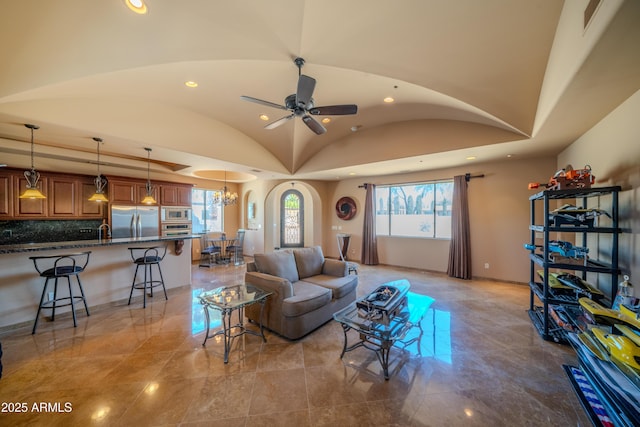 living room with visible vents, arched walkways, recessed lighting, vaulted ceiling, and ceiling fan with notable chandelier