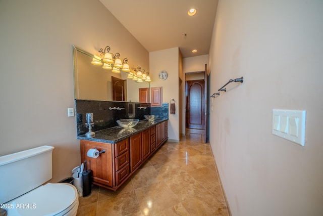 bathroom featuring baseboards, toilet, recessed lighting, vanity, and backsplash