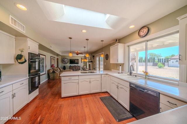 kitchen featuring dobule oven black, dishwasher, a sink, visible vents, and a peninsula