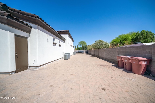 view of home's exterior with stucco siding, fence, a patio, central AC unit, and a tile roof