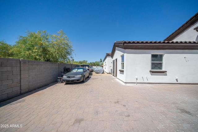 view of home's exterior with fence, stucco siding, and a tiled roof