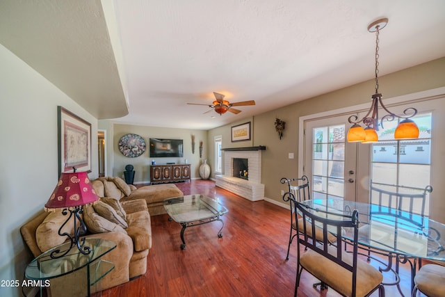 living room featuring a ceiling fan, baseboards, wood finished floors, and a fireplace