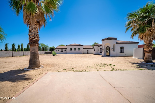 mediterranean / spanish house featuring a patio, fence, stucco siding, and a tile roof