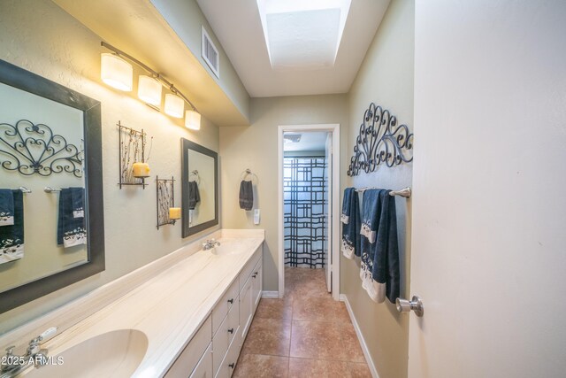 bathroom featuring a sink, double vanity, visible vents, baseboards, and tile patterned floors