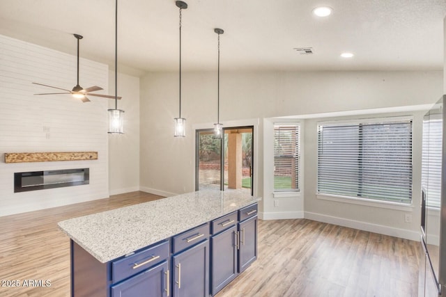 kitchen featuring ceiling fan, a center island, blue cabinetry, hanging light fixtures, and vaulted ceiling