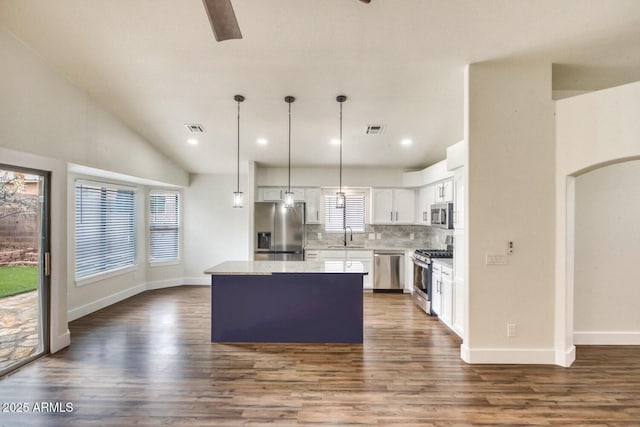 kitchen with a center island, appliances with stainless steel finishes, tasteful backsplash, hanging light fixtures, and white cabinets