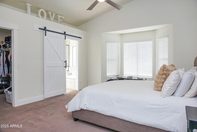 carpeted bedroom featuring ensuite bath, a barn door, a closet, ceiling fan, and lofted ceiling