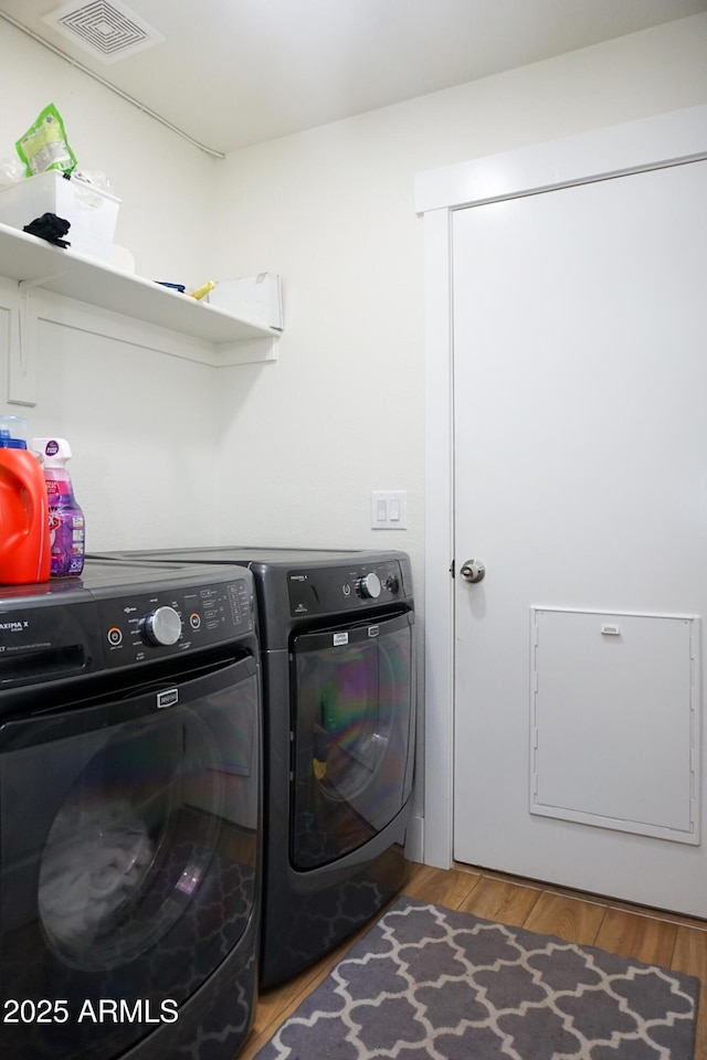 clothes washing area with wood-type flooring and washer and dryer