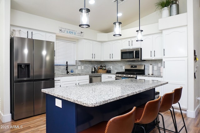 kitchen featuring stainless steel appliances, a center island, backsplash, and decorative light fixtures