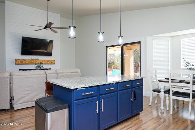 kitchen with dark hardwood / wood-style flooring, decorative light fixtures, blue cabinets, light stone counters, and a center island