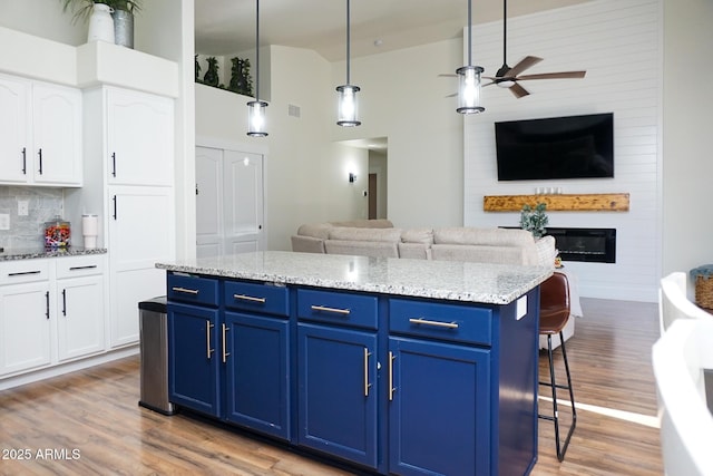 kitchen with decorative light fixtures, blue cabinetry, white cabinetry, and a center island