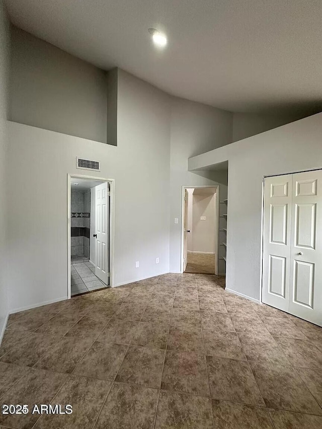 14002 N 49th Ave Unit 1120, Glendale, AZ 85306 - unfurnished bedroom with high vaulted ceiling, tile patterned floors, ensuite bathroom, baseboards, and a closet