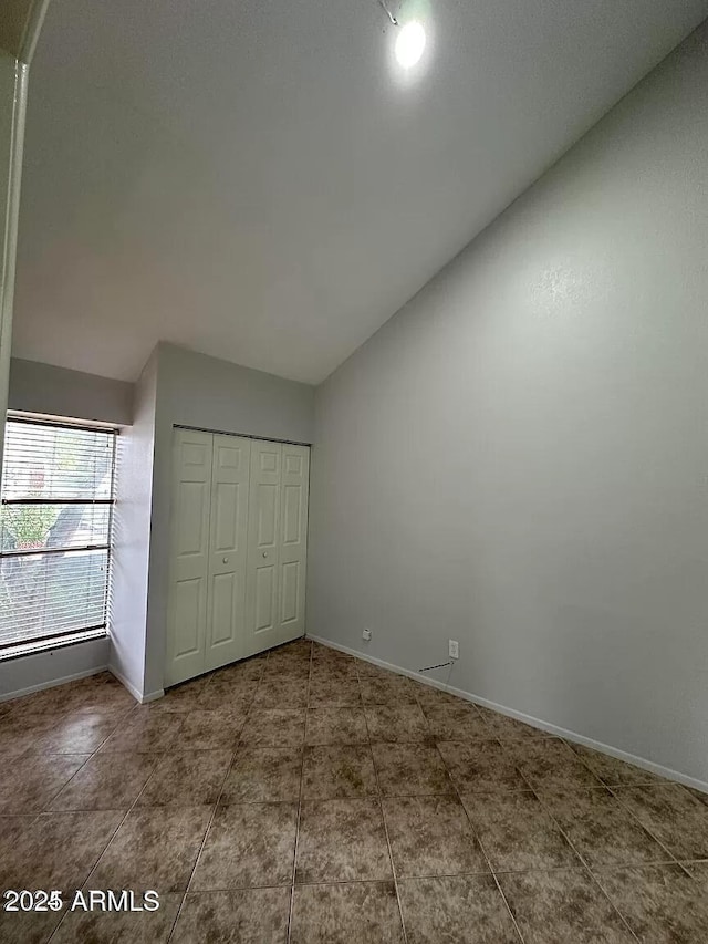 14002 N 49th Ave Unit 1120, Glendale, AZ 85306 - unfurnished bedroom with lofted ceiling, baseboards, tile patterned flooring, and a closet