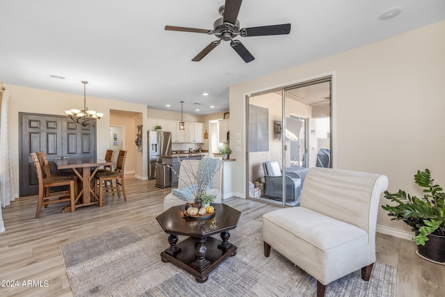 living room with ceiling fan with notable chandelier and light wood-type flooring