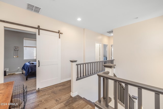 corridor with a barn door and hardwood / wood-style floors