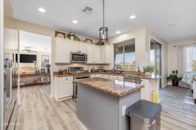 kitchen with stone counters, a kitchen island, light hardwood / wood-style flooring, appliances with stainless steel finishes, and white cabinetry