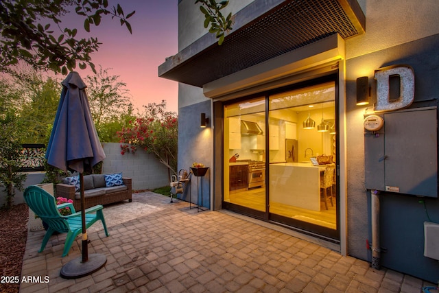 patio terrace at dusk with an outdoor living space, fence, and a sink