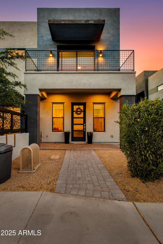 view of front of property with covered porch, a balcony, and stucco siding