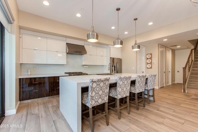 kitchen with modern cabinets, wall chimney range hood, stainless steel refrigerator with ice dispenser, light countertops, and white cabinets