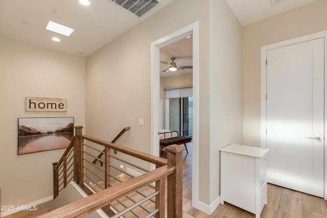 hall featuring visible vents, baseboards, an upstairs landing, light wood-style floors, and recessed lighting