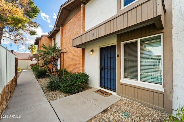 property entrance featuring fence and stucco siding