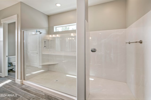 bathroom with toilet, wood-type flooring, and a shower with shower door