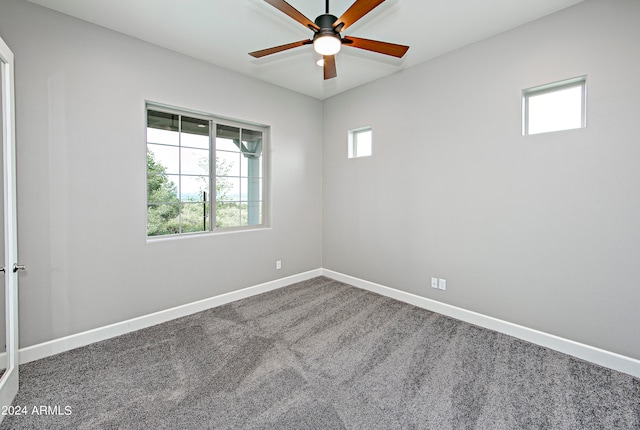 unfurnished room with ceiling fan and dark carpet