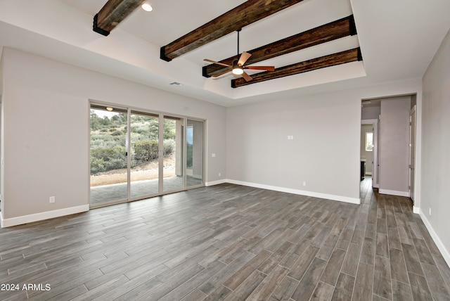 spare room featuring a tray ceiling, ceiling fan, wood-type flooring, and beam ceiling